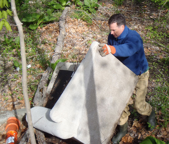 Ross Ogden moves a couch found near the Mill River along Congress Street April 28. Not far from there a TV satellite dish added was found. (John Kovach photo)