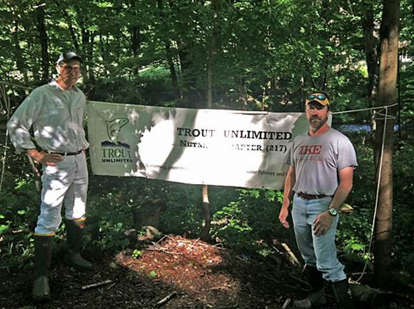 Bob Campbell and Mike Rowinsky with the sign that lets passers-by know who's cleaning up the side of the Mill River along Congress Street.