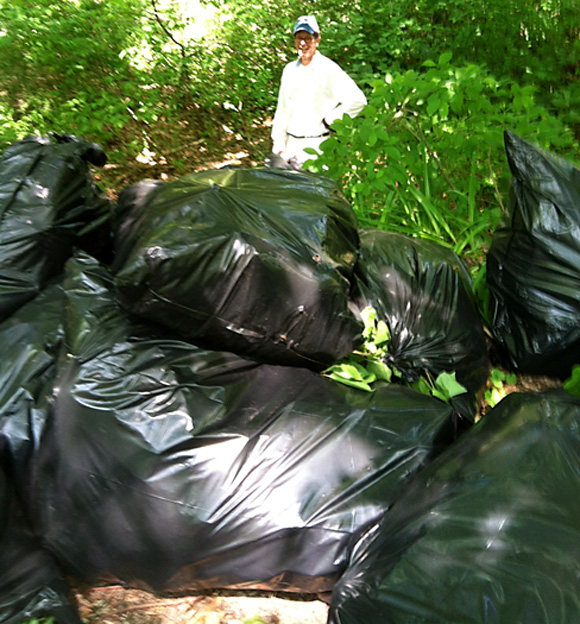 Bob Campbell stacks bags filled with Japanese Knotweed cut and removed from the banks of the Mill River along Congress Street. The nearly 20 bags stacked represent only a few hours work on the project.